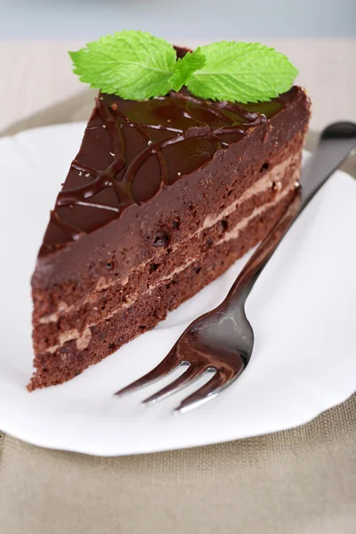 Stück Schokoladenkuchen auf Teller auf Holztisch vor natürlichem Hintergrund — Stockfoto