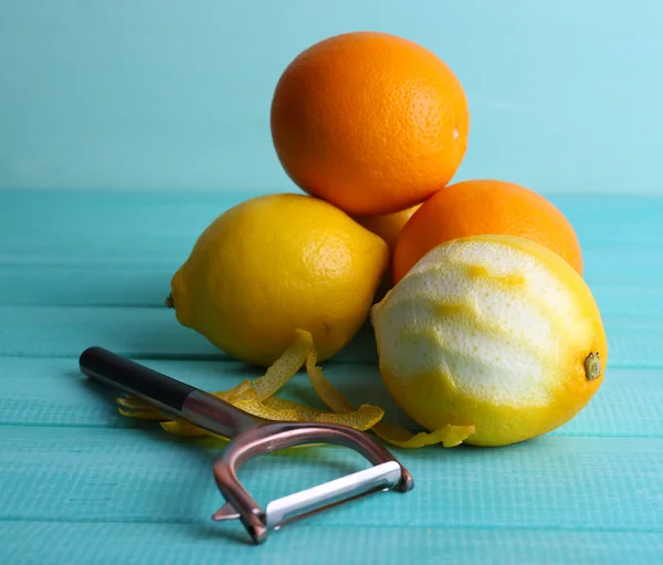 Lemons and oranges and peeling knife on blue wooden background — Stock Photo, Image