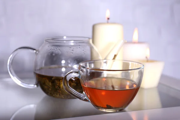 Σύνθεση με τσάι σε τσαγιέρα γυαλί και κεριά στο τραπέζι, επάνω ελαφρύς υπόβαθρο — Φωτογραφία Αρχείου