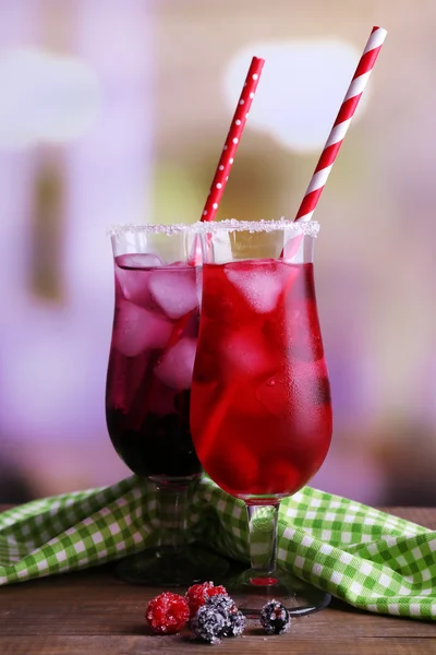 Glasses of cold berry cocktail and napkin on wooden table — Stock Photo, Image