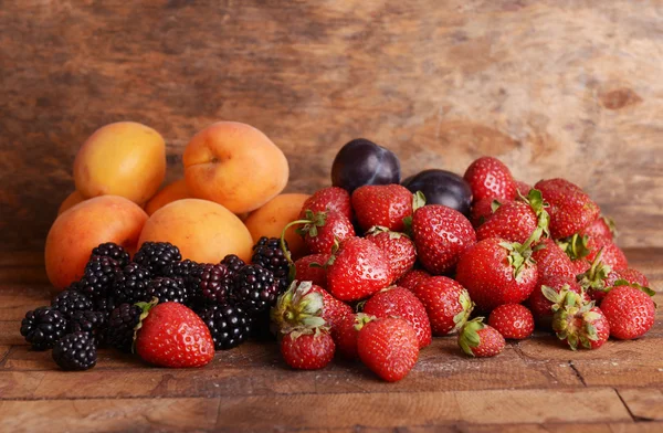 Frutas maduras e bagas em fundo de madeira — Fotografia de Stock