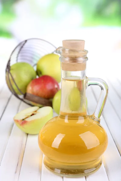 Cuka sari apel dalam botol kaca dan apel matang segar, di atas meja kayu, di latar belakang alam — Stok Foto