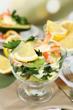 karides ve cam kapta ve parlak zemin üzerine ahşap masa üzerinde plaka üzerinde avokado lezzetli Salatalar