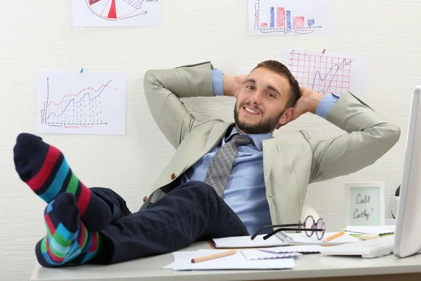 Empresário confiante segurando suas pernas em meias engraçadas na mesa — Fotografia de Stock