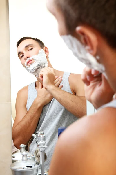 Jovem barbear sua barba no banheiro — Fotografia de Stock