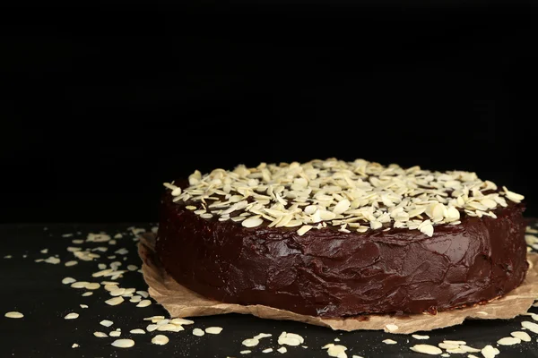 Bolo de chocolate saboroso com amêndoa, na mesa de madeira, no fundo escuro — Fotografia de Stock