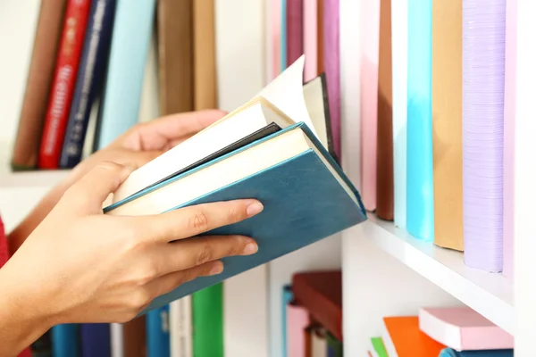 Livro de escolha de mão na biblioteca — Fotografia de Stock