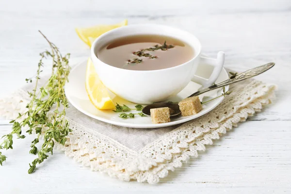 Taza de sabroso té de hierbas con tomillo y limón en la mesa de madera — Foto de Stock