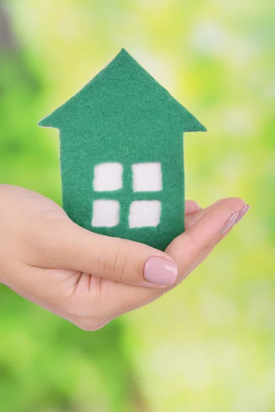 Woman hand holding paper house on bright background — Stock Photo, Image