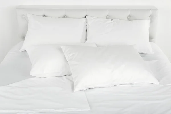 Белые подушки на кровати крупным планом — стоковое фото
