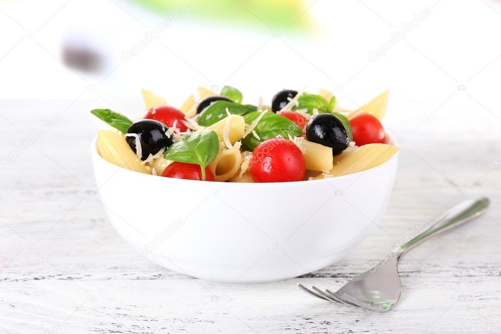 Pasta with tomatoes, olives and basil leaves