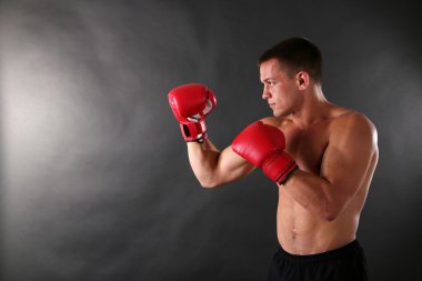 어두운 배경에서 권투 장갑과 잘생긴 젊은 근육 스포츠맨
