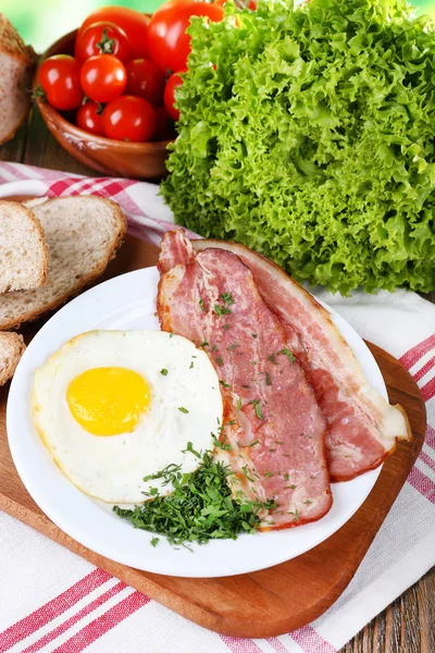 Œufs brouillés avec bacon et légumes servis dans une assiette sur une serviette — Photo
