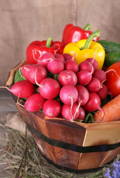Gran canasta redonda con hierba seca, verduras y huevos frescos sobre fondo de saco — Foto de Stock