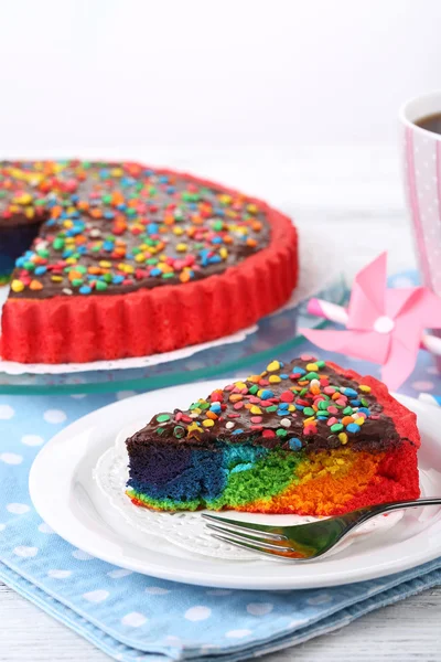 Delicious rainbow cake on plate, on table, on light background — Stock Photo, Image