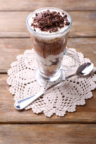 Yoghurt, met chocolade crème, gehakte chocolade en muesli geserveerd in glas op houten achtergrond — Stockfoto