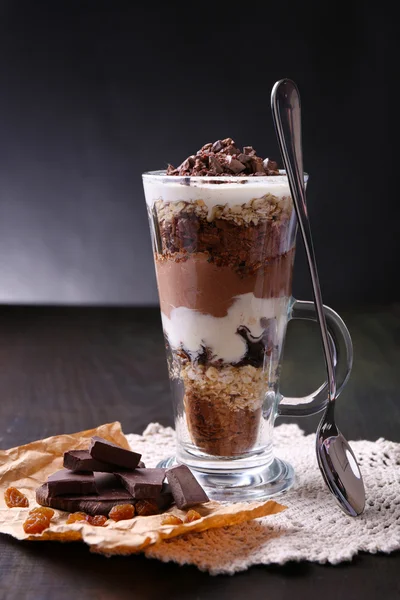 Yogurt, with chocolate cream, chopped chocolate and muesli served in glass on wooden background — Stock Photo, Image