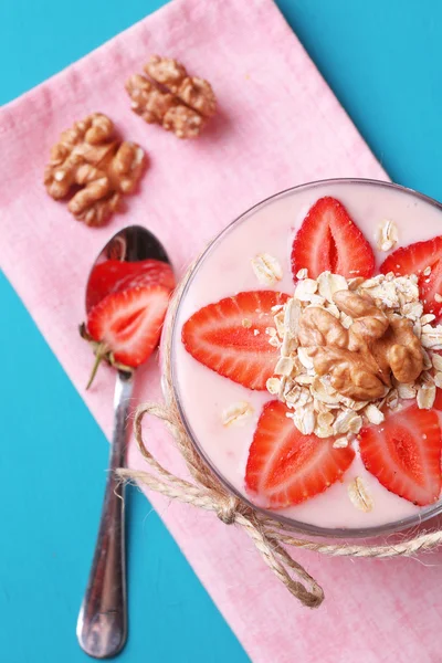 Gezond ontbijt - yoghurt met aardbeien en muesli geserveerd in glazen pot, op een houten achtergrond kleur — Stockfoto