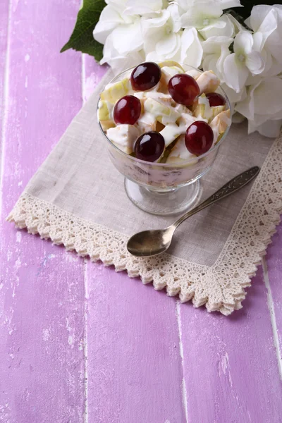 Desayuno saludable yogur con rodajas de uva fresca y manzana y muesli servido en un tazón de vidrio, sobre fondo de madera de color — Foto de Stock