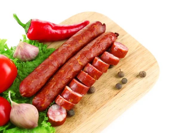 Smoked thin sausages and vegetables on cutting board, isolated on white — Stock Photo, Image