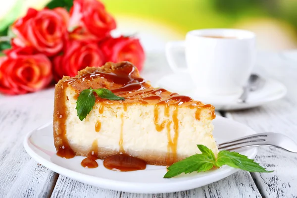 Bolo de queijo em prato e tufo de rosas na mesa no fundo da natureza — Fotografia de Stock