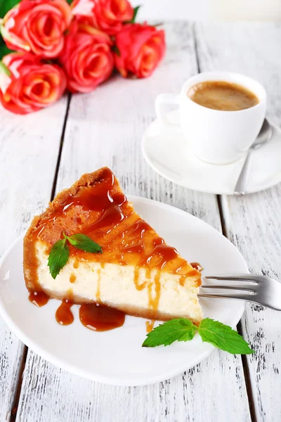 Torta di formaggio in piatto e ciuffo di rose su fondo di legno — Foto Stock