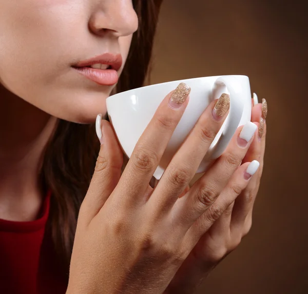 Hermosa joven con taza de café sobre fondo marrón — Foto de Stock