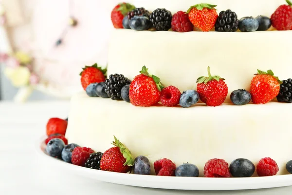 Bolo de casamento bonito com bagas na mesa de madeira, no fundo claro — Fotografia de Stock