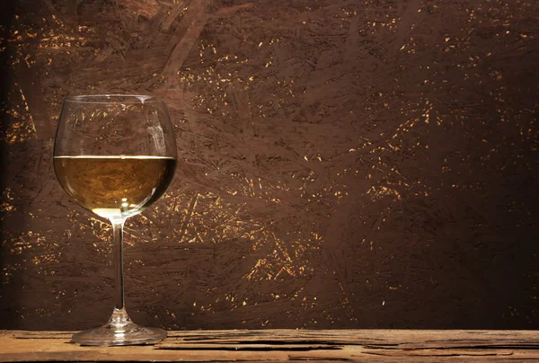 Glass of white wine on wooden table on wooden wall background — Stock Photo, Image