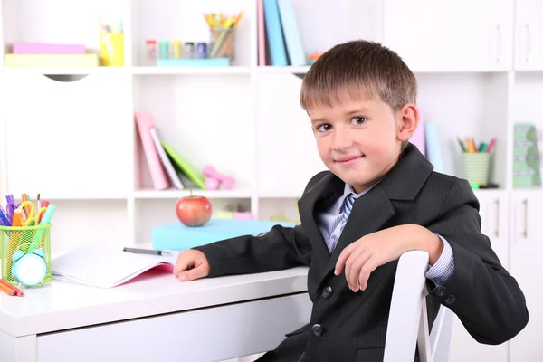 Skolpojke sitter vid bord i klassrummet — Stockfoto