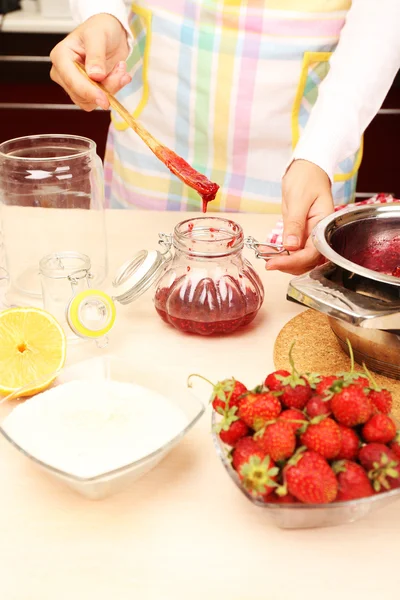 Mujer cocinando mermelada de fresa en la cocina —  Fotos de Stock