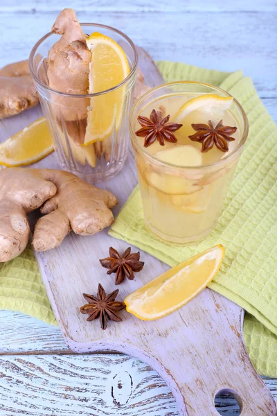 Verres de boisson au gingembre avec citron sur serviette sur planche à découper sur fond en bois — Photo