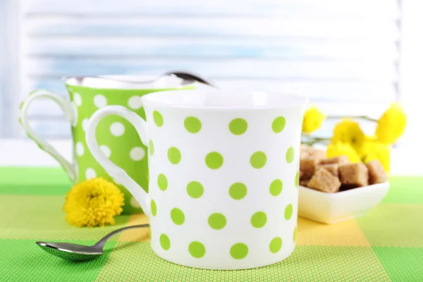 Zwei Polka Dot-Tassen mit Zucker und Wildblumen auf Tisch mit hellem Hintergrund — Stockfoto