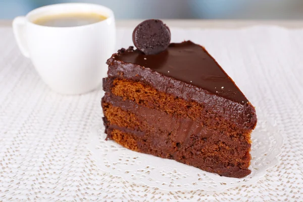 Pedaço de bolo de chocolate na placa e xícara de café no guardanapo no fundo do tecido — Fotografia de Stock