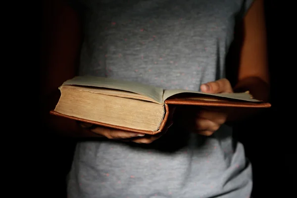 Donna in possesso di libro molto vecchio con polvere, su sfondo scuro — Foto Stock