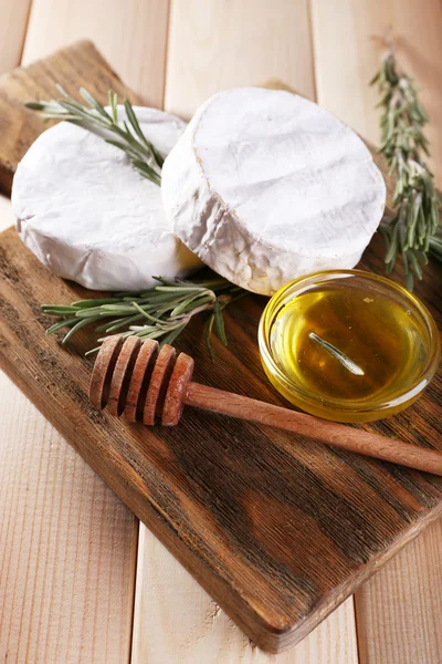 Queso camembert y miel en cuenco de vidrio sobre tabla de cortar sobre fondo de madera — Foto de Stock