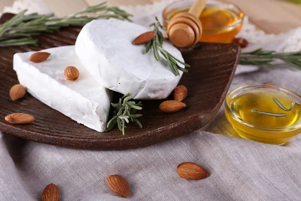 Brie y queso Camembert con nueces en el plato, miel en tazón de cristal en servilleta sobre fondo de madera — Foto de Stock