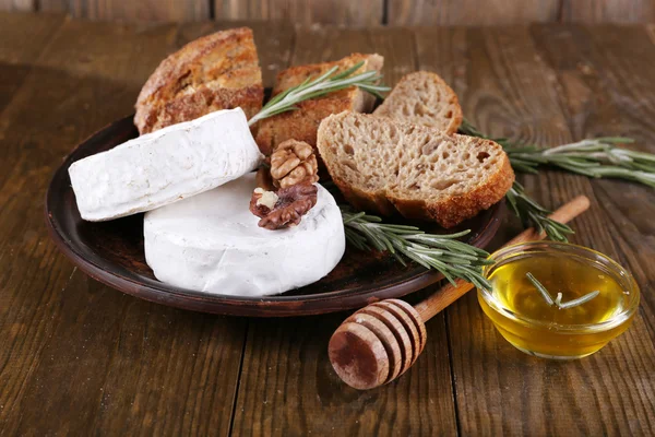 Camembert cheese on plate, honey, nuts and bread on wooden background — Stock Photo, Image