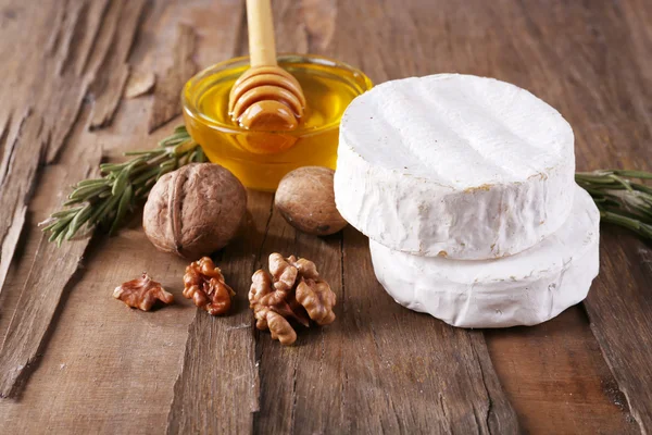 Queso camembert, nueces y miel en cuenco de vidrio sobre fondo de madera — Foto de Stock