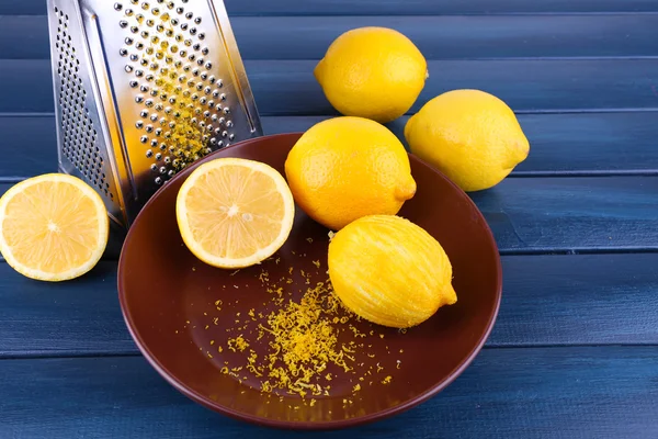 Lemons on plate and grater on dark blue wooden background — Stock Photo, Image