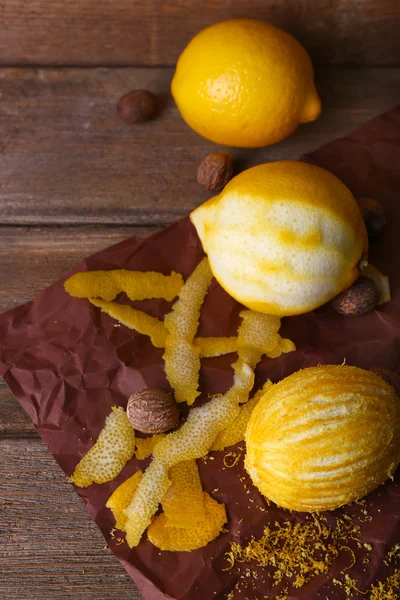 Lemons, nuts and grater on paper on wooden background — Stock Photo, Image