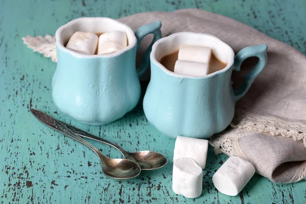 Xícaras de café com marshmallow e guardanapo na mesa de madeira — Fotografia de Stock