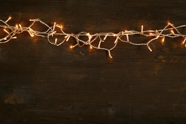 Christmas lights on wooden background — Stock Photo, Image