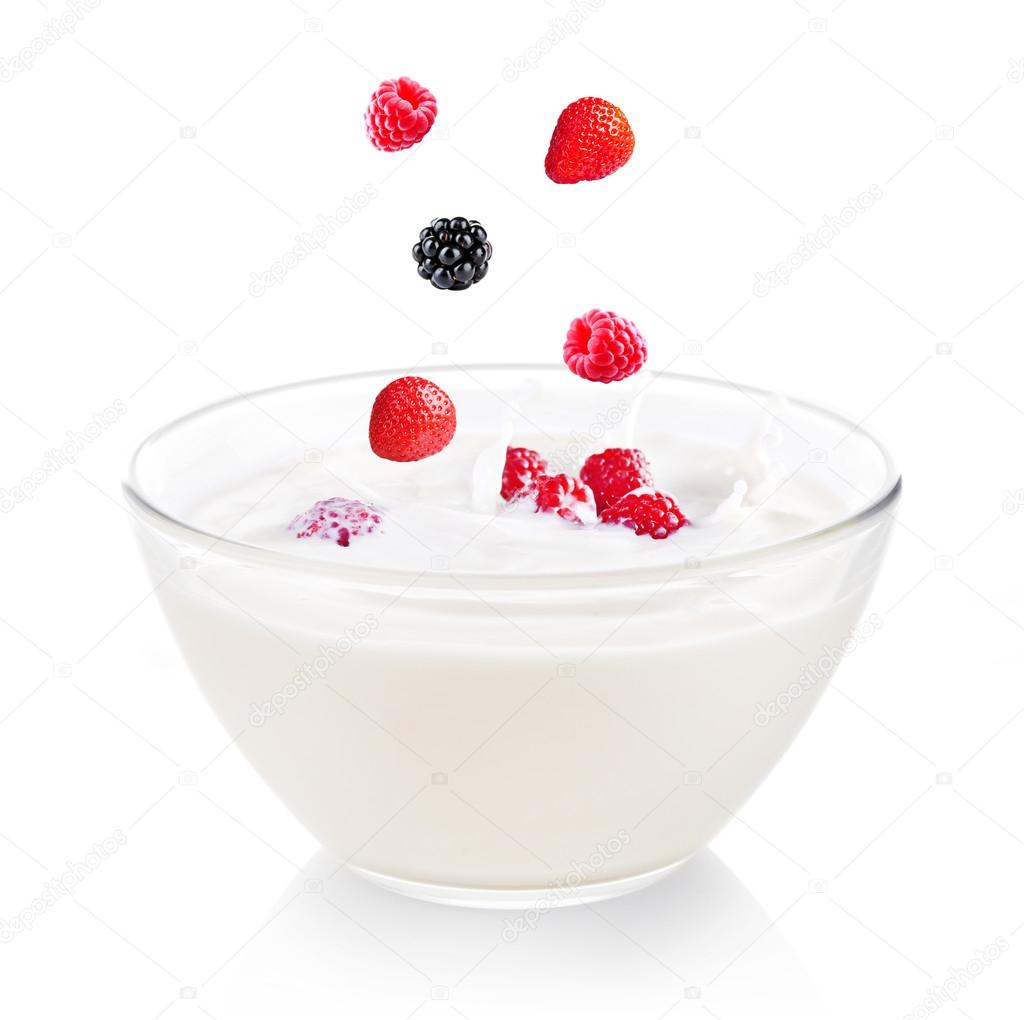 Delicious fresh berries falling into bowl of yogurt isolated on white