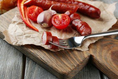 Ahşap arka plan üzerinde kesme tahtası üzerinde sebze ve ince Sosis füme