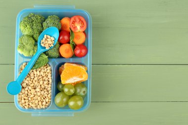 Yeşil ahşap masa üzerinde plastik kutu lezzetli Vejetaryen yiyecekler