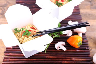 Bambu hasır ahşap arka plan üzerinde paket servisi olan restoran kutularındaki Çin eriştesi