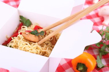 Çin eriştesi ve paket servisi olan restoran kutusunda kumaş arka plan üzerinde sopa