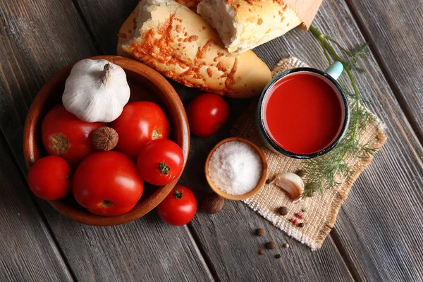 Homemade tomato juice in color mug, bread sticks, spices and fresh tomatoes on wooden background — Stock Photo, Image