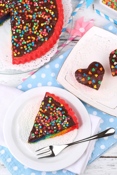 Deliziose torte arcobaleno sul piatto, sul tavolo, su sfondo luminoso — Foto Stock